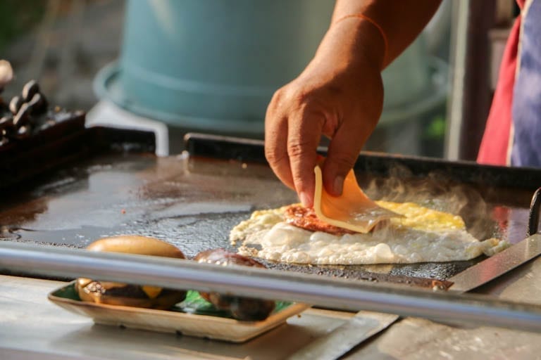 This Kuala Lumpur street food is a burger wrapped in fried egg, cheese, onions, and worcestershire sauce