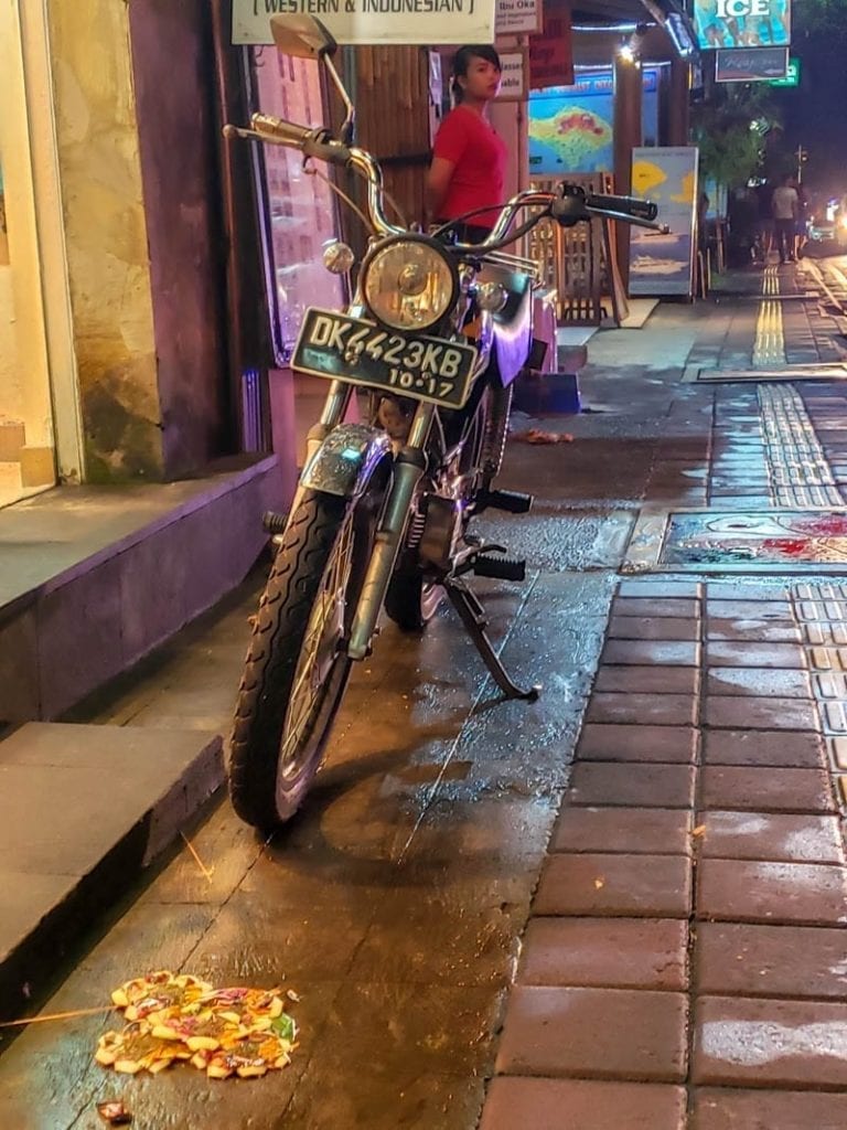 A scooter parked on Monkey Forest Road near an offering to the spirits.