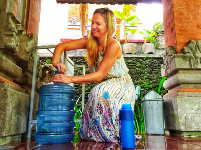 Using a five-gallon jug to pour water into a collapsible water bottle. The water bottle belongs at the top of your eco-friendly travel products list!