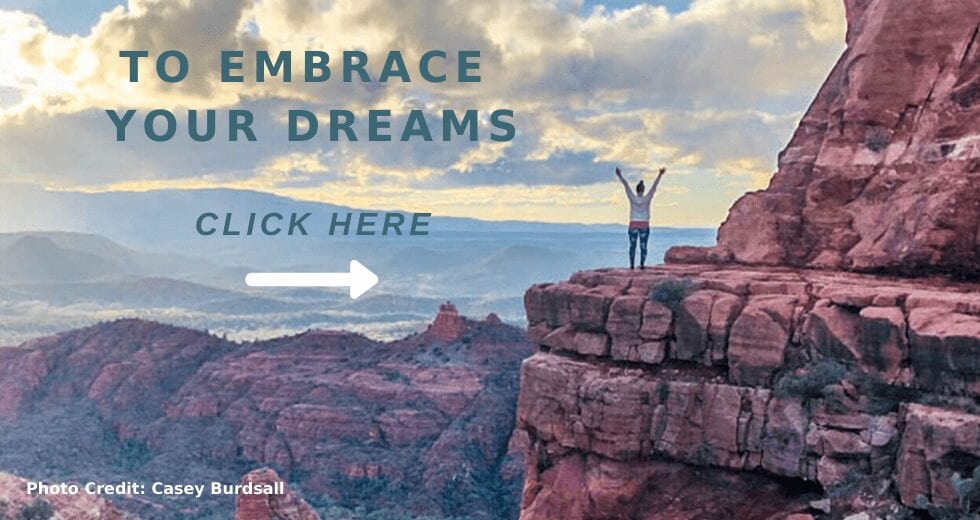 Woman holding arms up toward sky on vortex in Sedona Arizona