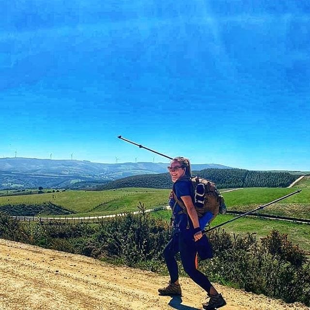 Woman celebrates summiting a mountainous hill on the Camino del Norte