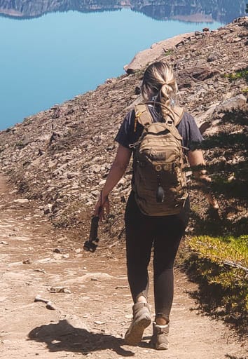 Woman walking on Garfield Peak Trail with Crater Lake in distance